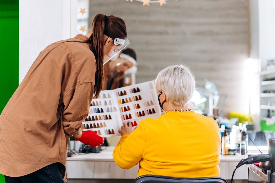A hairstylist consults with a client using hair color samples in a salon setting.